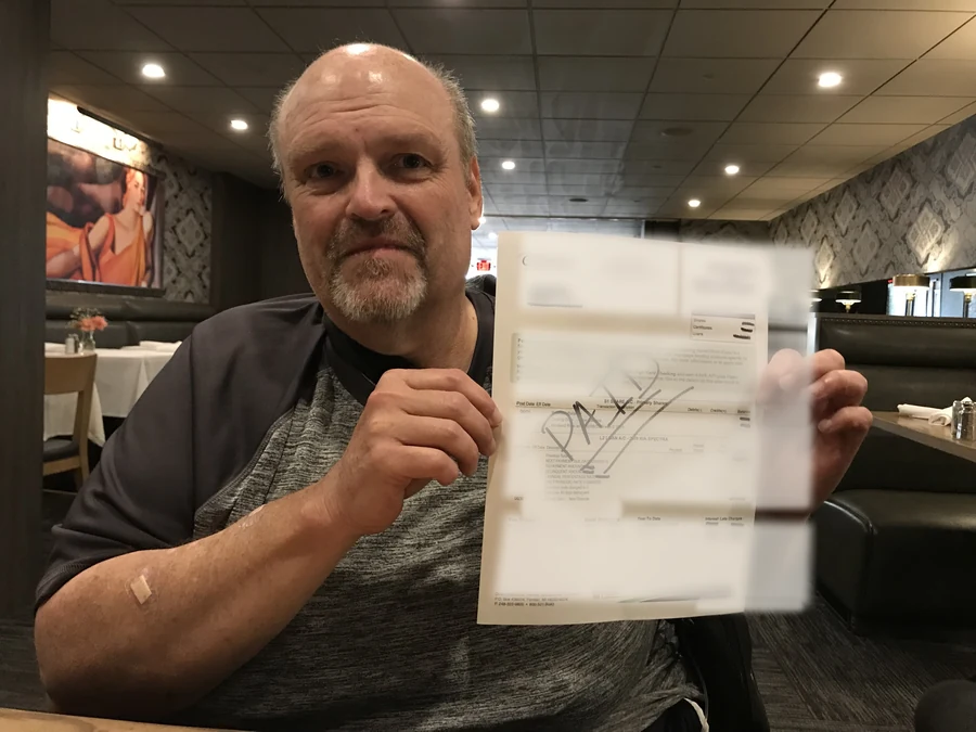 Clyde at a restaurant holding a privacy-protected page from a One More Moment experience